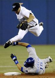Toronto Blue Jays shortstop Jason Smith, top, jumps to avoid Kansas City Royals' Mark Grudzielanek. Grudzielanek was safe at second in the Royals' 6-3 victory Tuesday in Toronto.