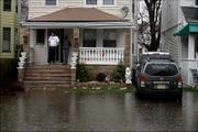 Pedro Dominguez stands on his front porch in Hackensack, N.J., where the flood waters were rising up his steps as his wife, Gina, stands with him Sunday. A powerful nor'easter pounded the East with wind and pouring rain Sunday, grounding airlines and threatening to create some of the worst coastal flooding some areas had seen in more than a decade.