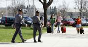Officers of the Virginia State Police provide security as students return Sunday to the Virginia Tech campus in Blacksburg, Va. Students, from left, Julie Huff, Annie Ellis, and Vanessa Tumminia, carry their belongings into West Ambler Johnston Hall. Students are returning to the campus as classes will resume today.
