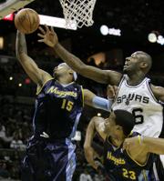 Denver forward Carmelo Anthony (15) grabs a rebound in front of San Antonio Spurs center Francisco Elson as Nuggets center Marcus Camby looks on. The Nuggets won, 95-89, Sunday in San Antonio.