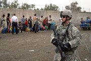 A U.S. soldier stands by as Iraqis wait to get fuel at a station in Baghdad. The Democratic-controlled U.S. Senate adopted House-passed legislation calling for troops to begin leaving Iraq by Oct. 1, a move that's drawing mixed reaction among Iraqis.