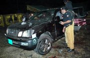 Pakistani police officers examine the damaged vehicle of Pakistan Interior Minister Aftab Khan Sherpao at the site of suicide bombing Saturday in Charsadda, Pakistan. A suicide bomber attempted to kill Pakistan's interior minister in an attack at a political gathering in a northwestern town that left at least 22 dead and 35 wounded, officials said.