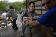 Volunteer Jeff Eubanks, right, Lawrence, hands a box of nonperishable food to Paul Hunt, director of human service programs at the Ballard Community Center, as the two, along with Lawrence volunteers Julie Cooper and Bruce Muzzy, move food Wednesday morning from a delivery truck outside the Ballard Center to various organizations. The Ballard Center will be one of several nonprofit organizations to benefit from Saturday's National Association of Letter Carriers Food Drive. Letter carriers will collect nonperishable food items from doorsteps and near mailboxes.