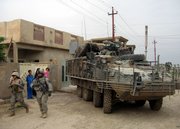 U.S. soldiers on foot and a Stryker armored vehicle move through a neighborhood in Ramadi, Iraq, 70 miles west of Baghdad on April 27. A string of heavy losses from powerful roadside bombs is raising new questions about the vulnerability of the Stryker, the Army's troop-carrying vehicle hailed by supporters as the key to a leaner, more mobile force.
