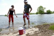 Kristi Wenger and Mitch Langley, both of Lawrence, find the swim beach area and parking lot under water on the west side of Clinton Lake. The lake is at its second highest level in history thanks to the big rains of the last couple of weeks. Wenger and Langley had hoped to swim Monday but settled for sunbathing in the grass near the high water.