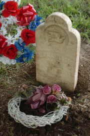 Wreaths lie near the tombstone of Anna Jessie, who died at age 5 in 1878, at Clinton Cemetery. The tombstone, which a farmer found on his land, was moved last fall from the Wakarusa River Valley and Heritage Museum to the cemetery.