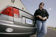 Laurie With is shown next to her Honda Civic hybrid in Sauk Rapids, Minn. With has adopted several driving techniques that allow her to squeeze every bit of distance she can out of every drop of gas.