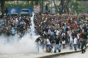 University students throw back tear gas canisters fired by riot police, unseen, in Caracas during protests against Venezuelan President Hugo Chavez's decision to shut down television station Radio Caracas Television. Thousands of people, both opponents and supporters of the move, took to the streets in protest Tuesday.