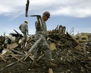 An Army Reserve member removes metal from a pile of debris while helping clean storm damage in Greensburg. Most of the town of 1,400 was destroyed after an F-5 tornado hit the community May 4, 2007, and exposed vulnerabilities in the region’s emergency response system.