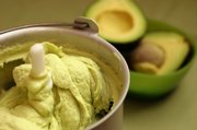 Avocado ice cream is churned in a home ice cream maker. The smooth and creamy frozen treat has a striking green color.