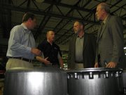 Jim Stinehelfer, CEO of HiPer Technology Inc., second from left, leads a tour of the company's manufacturing floor at 2920 Haskell Ave., including a stop at a stack of HiPer's carbon composite wheels. Listening are, from left, Chris Bovis, director of marketing for HiPer; state Rep. Tom Sloan, R-Lawrence; and David Kerr, Kansas secretary of commerce. Below is one of the company's wheels.