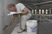 Tom Thompson, a carpenter with Howard Stultz Construction, works on plastering damaged walls inside an open area in Spooner Hall. The room is being renovated and named the "Commons."