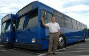 On July 2, 2007, KU on Wheels changed to new buses. Danny Kaiser, assistant director of KU Parking and Transit, with two of the new 40-foot buses, points out the new paint scheme for the buses.