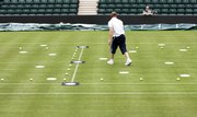 Technicians prepare the tennis court for calibration of the "Hawk-Eye" video line call system. The All England Club will use the system on two of its courts at Wimbledon this year.