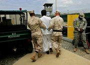 A Guantanamo detainee, center, is escorted by U.S. military personnel on the grounds of the detention facility at Guantanamo Bay, Cuba, in this May 15 file photo. The Bush administration is nearing a decision to close the detention facility and move the terror suspects to military prisons elsewhere, including Fort Leavenworth.