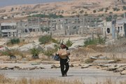 A Palestinian man carrying a child walks toward the Erez Crossing, Thursday in the northern Gaza Strip. Hundreds of people rushed to the crossing after the Hamas takeover, among them Fatah loyalists who feared they'd be harmed by Hamas, despite the militants' offer of amnesty. By Thursday, the passage was nearly empty after it became clear that a mass exit to the West Bank was not approved. The building in the background was part of an Israeli industrial area that was destroyed after Israel pulled out of Gaza in 2005.