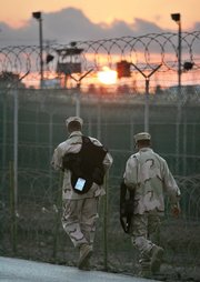 U.S. troopers walk as the sun rises over the razor-wired detention compound at Guantanamo Bay U.S. Naval Base, Cuba, in December 2006. The Bush administration is nearing a decision to close the Guantanamo Bay detainee facility and move its terror suspects to military prisons elsewhere.