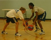 KU women's basketball player Sade Morris, right, jokes with camper Michaela Neuhus, 13, of Denver during a dribbling drill. Morris is a member of a six-player sophomore class.