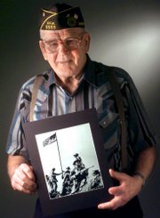 Charles W. Lindberg, one of the U.S. Marines who raised the first American flag over Iwo Jima during World War II, holds a photo of the event in this June 7, 1999, photograph in Grand Forks, N.D. He is standing behind the Marine holding a rifle. Lindberg died Sunday at age 86.