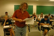 David Dewar, an assistant director of the humanities and Western Civilization program at Kansas University, distributes materials to students before class Thursday. Tuition rates at KU will go up this fall as part of a plan approved Thursday by the Kansas Board of Regents.