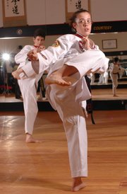 Dru Forrester, left, and Fe Brinkley, both of Lawrence, earned world champion honors at a recent tae kwon do competition. They and three other students at the ATA Black Belt and Leadership Academy, 5150 Clinton Parkway, were named world champions at a competition in Little Rock, Ark. The two recently practiced some kicks at the academy.