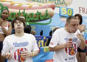 Takeru Kobayashi, left, and Joey Chestnut, right, eat hot dogs during Nathan's Famous Hot Dog Eating Competition Wednesday in New York. Chestnut emerged as the world's hot dog-eating champion by gobbling down a record 66 franks.