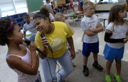 Sophia Walters, 8, left, and group leader Mercades Beckum sing karaoke to Whitney Houston&squot;s "I Wanna Dance with Somebody" as they play the video game SingStar on Friday morning during the Boys and Girls Club Summer Camp at Cordley School.