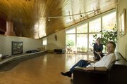 Tom Harper, foreground, started the process to add the hyperbolic paraboloid house at 934 W. 21st St. to national and state historic registers. Harper and resident Maria Holter, background, are shown in the living room of the unique modern home.