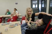 A KU student works with a child at the Sertoma-Schiefelbusch Communication Camp during the June session at the Douglas County 4-H Fairgrounds.