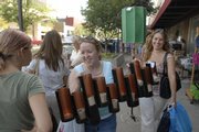 Michelle McCudden, foreground, and Racheal Ruble negotiate a crowded Massachusetts Street sidewalk as they tote home furnishings to their car. Thousands of bargain hunters filled downtown Lawrence on Thursday for the annual sidewalk sale.