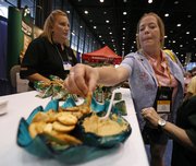 Robin Lightfoot, of Garden City, Kan., listens to Kathy Cheop as she samples hummus at the Wild Garden booth at the School Nutrition Association annual meeting this week in Chicago. The push for healthy options has food companies scurrying to find creative, healthy alternatives like single-serve portions of hummus that could become kid-friendly favorites.