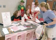 Rose Kelly, 20, left seated, and Tess Kelly, 17, check in Anne Frey, right, who donated blood at the Annual Frances Kelly Blood Drive in May in Manassas, Va. Frances, 2, pictured in the poster on the table, was left in a hot car by her father, Kevin Kelly. Part of Kelly's manslaughter sentence requires him to hold a blood drive every year around the anniversary of his daughter's death. Standing are cousins, from left, Ronan Dufrain, Mark Sheetz and Joseph Sheetz.