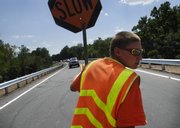 Vehicles line up at 3 p.m. to cross the Lecompton bridge for the first time in months Friday as Keesha Simmons starts flagging them across in Lecompton. Traffic was restricted to one lane because of painting delays. Douglas County Administrator Craig Weinaug said traffic should be open for both lanes today by midmorning.