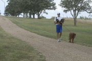Reigning Big 12 cross country champion Colby Wissel goes for a stroll with Molly (on leash) and Forest on the Haskell Indian Nations University campus. Wissel and the pooches go for a daily jog unless it's too hot, and the jog becomes a walk. Forest sometimes pants his way to a ride.