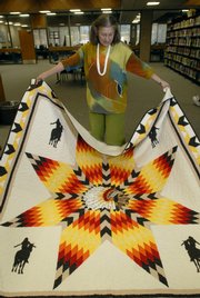 Marilyn Russell unfurls a quilt at Tommaney Hall at Haskell Indian Nations University. Haskell is opening "Native Threads," a traveling exhibit of quilts that represent native traditions.
