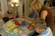 Harbor House residents Vince Van Sykle, left, Gladys Burge and Mary Davis help director Kitty Shea, standing, with preparing fruit for a snack. Shea and Robert Wilson opened Harbor House, 1126 Hilltop Drive, for seniors with Alzheimer's or dementia. Developers in Lawrence have expressed interest in creating more continuum-care facilities - those that address some or all stages for retirees who go on to independent living, assisted living or 24-hour care.