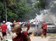 Buddhist monks and Myanmar citizens run past a motorcycle that was burned in Yangon, Myanmar, in this photo released by the National League for Democracy-Liberated Area. Security forces fired warning shots and tear gas canisters while hauling militant Buddhist monks away in trucks Wednesday as they tried to stop anti-government demonstrations in defiance of a ban on assembly.
