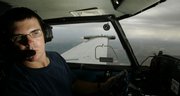 While a wing-mounted generator emits particles of silver iodide, Scott Bryant looks for cloud formations as he flies a cloud-seeding mission for the Western Kansas Weather Modification program Aug. 28 near Lakin. The program aims to reduce crop damage from hail by saturating storm clouds with silver iodide particles.