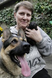 Gerlinde Schultze, 46, from Berlin, poses with her 1-week-old purebred East German shepherd puppy, Xaver, and Xaver's mom, Virginia. As the country celebrates 17 years of reunification, some animosities between the East and West remain, including the fight over which German shepherds are best.