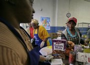 Marcia Watkis, far left, a volunteer at the Bedstuy Campaign Against Hunger, a food pantry that lets people in need shop for their own items, checks groceries for Merna Smith, right, Wednesday in the Brooklyn borough of New York.