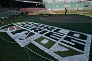 The grounds crew works behind the freshly painted World Series logo at Fenway Park. The Red Sox will entertain Colorado in Game 1 of the baseball World Series Wednesday.