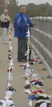 Hundreds of bras were strung across the Kansas River Bridge to raise breast cancer awareness. Hank Booth and Ian Rombough helped put up the display Friday.