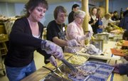 Lawrence volunteers, from left, Diane Fry, Robin Richards and Donna Obenland work the food line of the Lawrence Interdenominational Nutrition Kitchen as they serve Thanksgiving dinners Thursday at First Christian Church, 10th and Kentucky streets. An estimated 200 people attended the annual event.