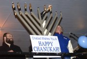 Miles Schnaer, right, of Lawrence, lights a 6-foot menorah with Rabbi Zalman Tiechtel of the Chabad Jewish Center in celebration of Hanukkah.
