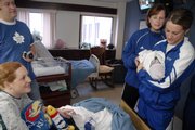 New parents Ben and Heidi Nelson, left, get a visit from Kansas University women's basketball coach Bonnie Henrickson, second from right and player Katie Smith, a junior from Omaha, Neb., who holds the Nelsons' 1- day-old son, Finn, on Tuesday at Lawrence Memorial Hospital. The women's basketball team visited patients and passed out Jayhawk gifts on their annual holiday tour of LMH.