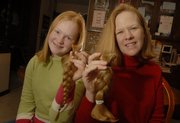 Morgan Linder and her mother, Renee Linder, of Baldwin City, display the hair they recently cut off for the Locks of Love program, which donates hair to children who have lost theirs because of illness.