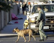 A police officer and dog walk through a crime scene Tuesday in Las Vegas. Assailants shot six young people Tuesday who had stepped off a bus coming from a high school, wounding two seriously, in a midday attack just blocks from two elementary schools, authorities said.