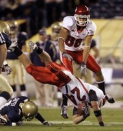 Utah's Ray Stowers (24) dives for a first down as teammate Freddie Brown leaps over the play during the first quarter of the Poinsettia Bowl. Utah won the first bowl game of the season, 35-32, over Navy on Thursday in San Diego.