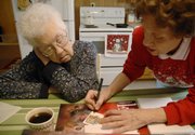 Patty Hoover helps her mother sign cards to accompany Christmas gift calendars for their family in this 2007 file photo. After Hoover&squot;s father died, the family realized that he had been covering for his wife&squot;s forgetfulness. "If you live out of state and don&squot;t come back very often, you are so excited about seeing them that you may not see those signs," said Hoover, who now lives in Eudora with her mother.