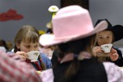 Hazel Ingram, 8, left, and Saya Eagleman, 8, sip tea Friday during the holiday tea party at Lawrence Public Library, 707 Vt. The party's theme was Western. Live music and a roping demonstration were among the activities.